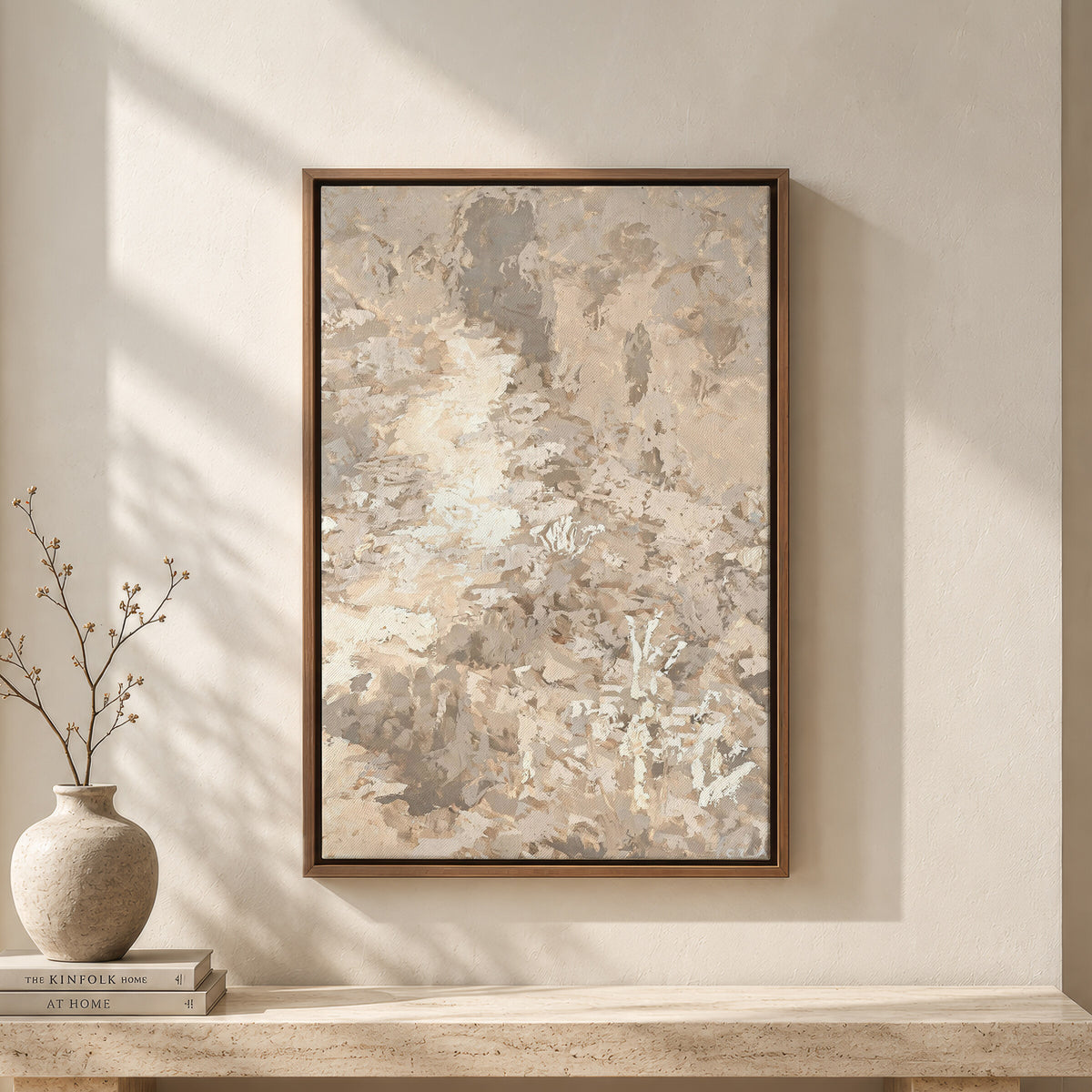 Soft Beige Foliage framed wall art above a travertine bench with a vase and books