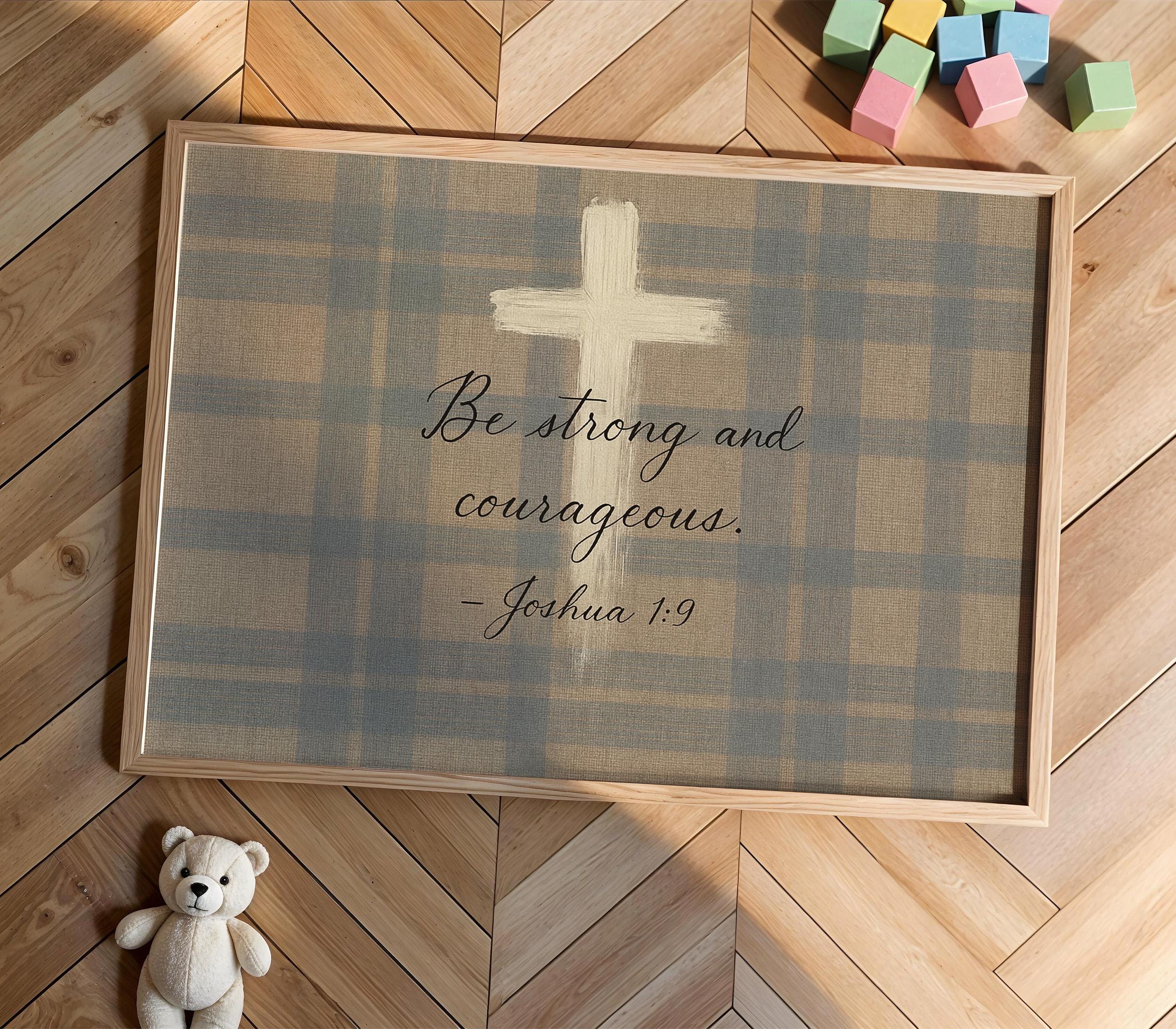 A framed Bible verse with a cross and the text "Be strong and courageous" is displayed on a wooden floor, accompanied by a teddy bear and colorful building blocks.