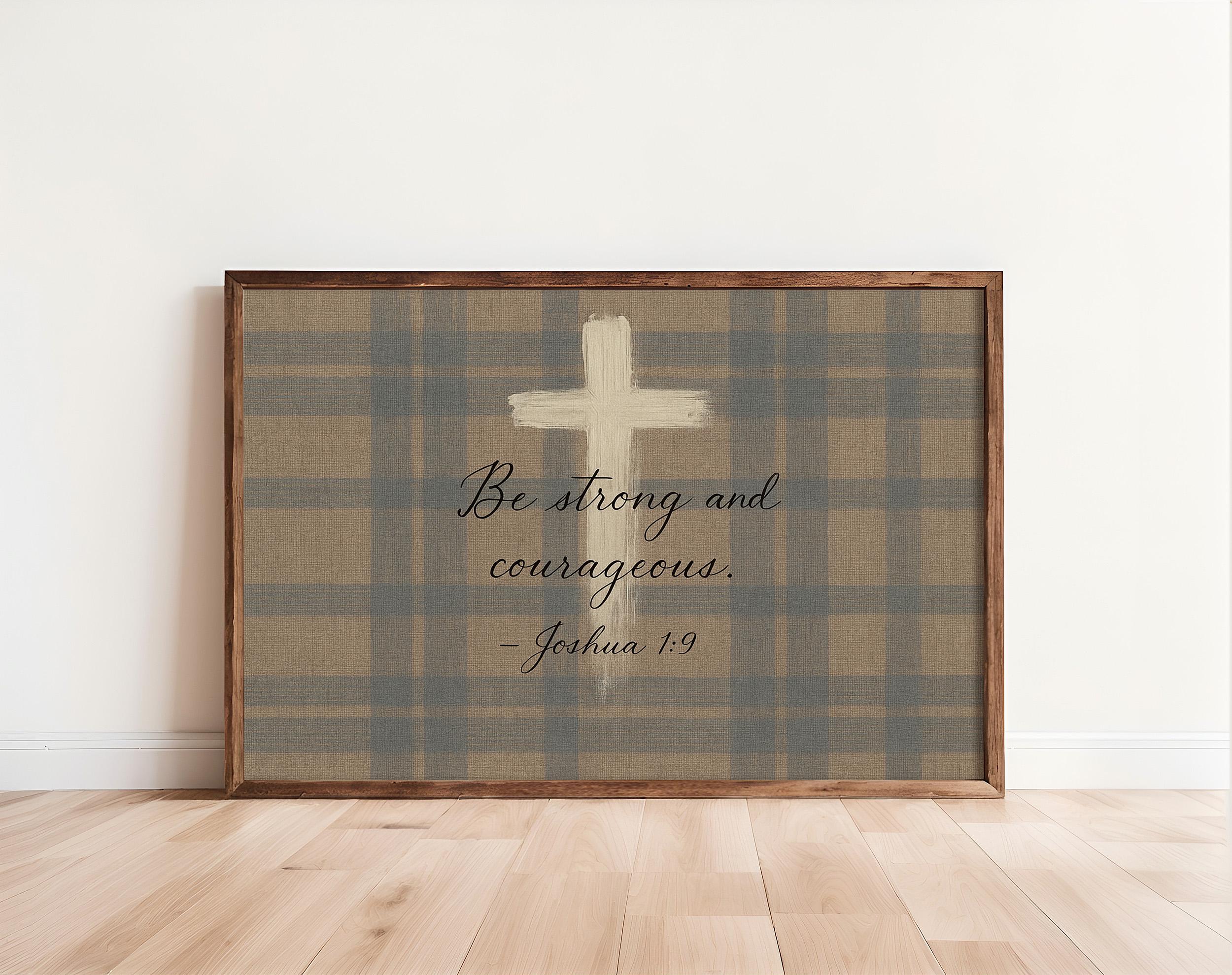A framed print with a plaid background and a white cross, along with a Bible verse from Joshua 1:9.